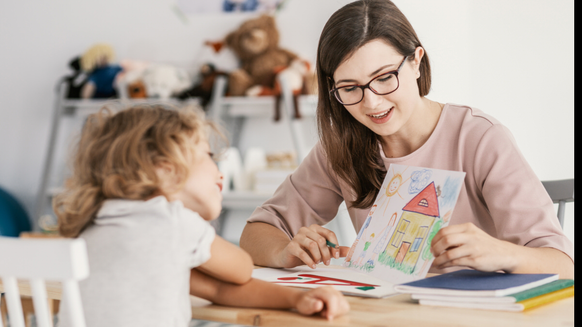 A therapist showing a child a drawing during a therapy or learning session