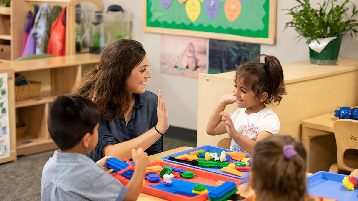 Teacher and young student high-fiving during an engaging classroom activity