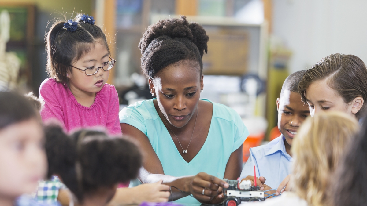 A teacher instructing young students on a hands-on project