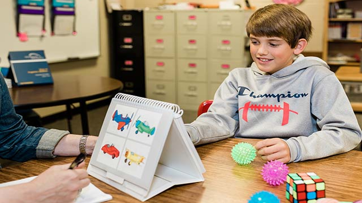 A boy working on a visual matching activity with colorful sensory balls