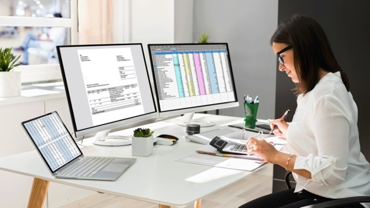 A woman working at a desk with data applications on multiple monitors