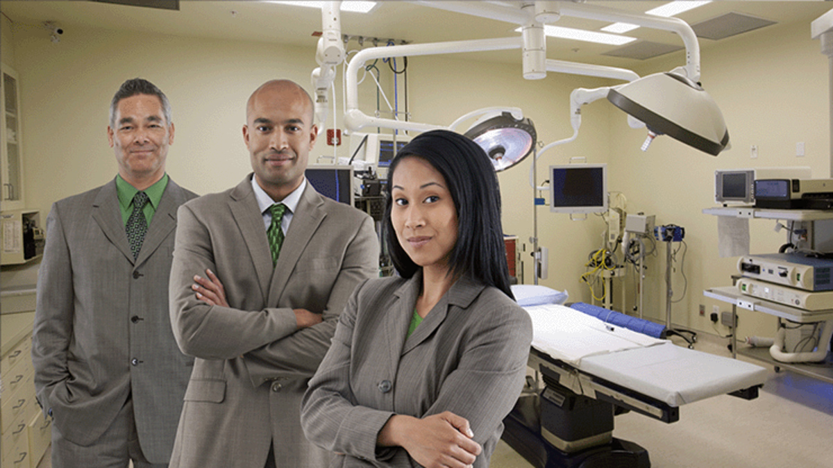 Three professionals in suits standing confidently in a hospital setting