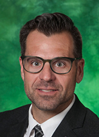 UNT faculty member Matt Walker in a portrait wearing business clothes in front of a green backdrop