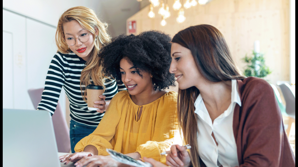 A group of women gathered around a laptop