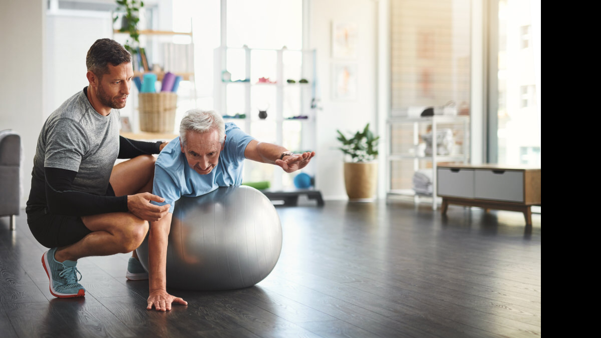 A physical therapist helping an elderly man exercise