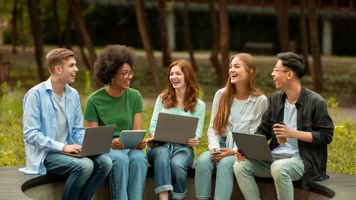 Students with laptops sitting in a circle and talking 
