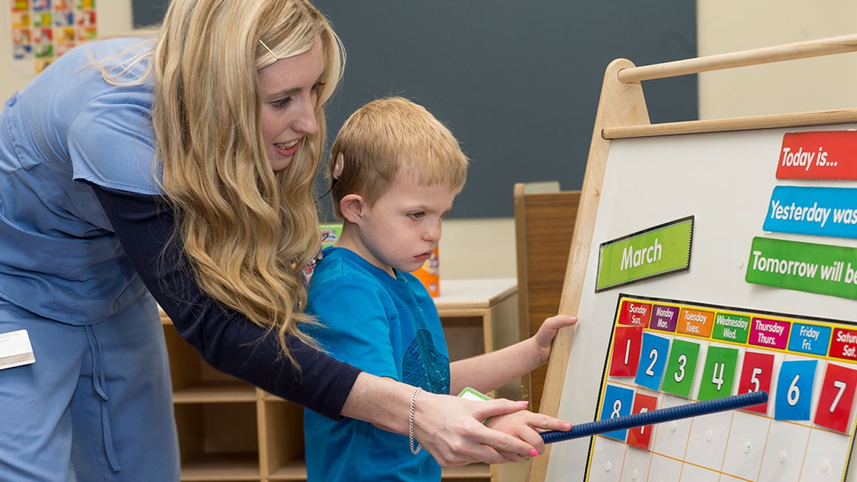 A teacher helping a boy to understand a calendar