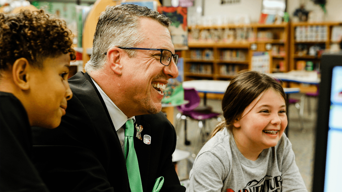 A smiling school administrator interacting with students