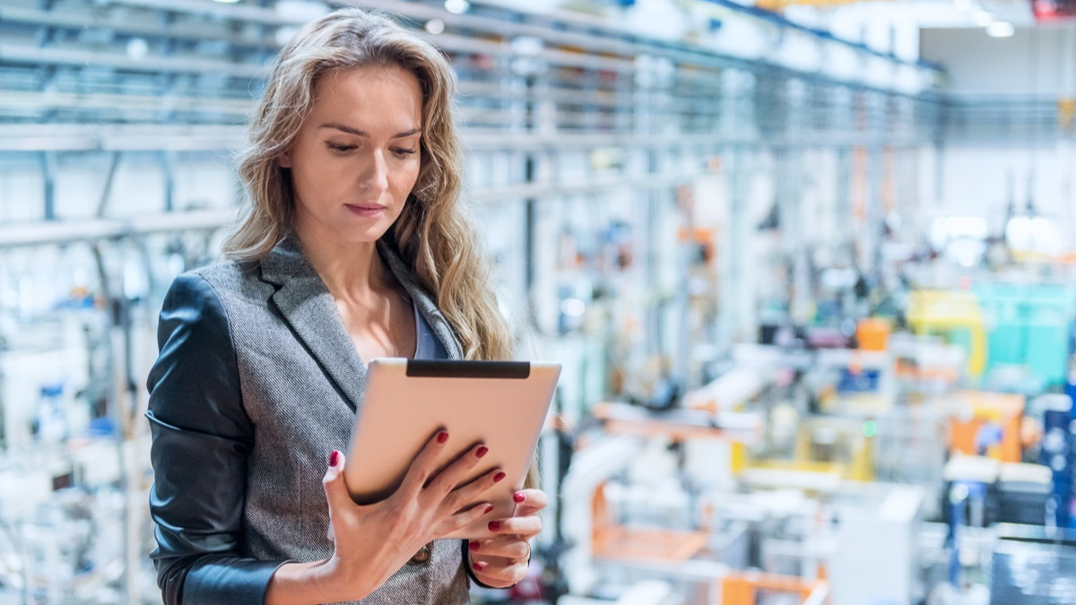 A professional using a tablet to oversee processes in modern manufacturing