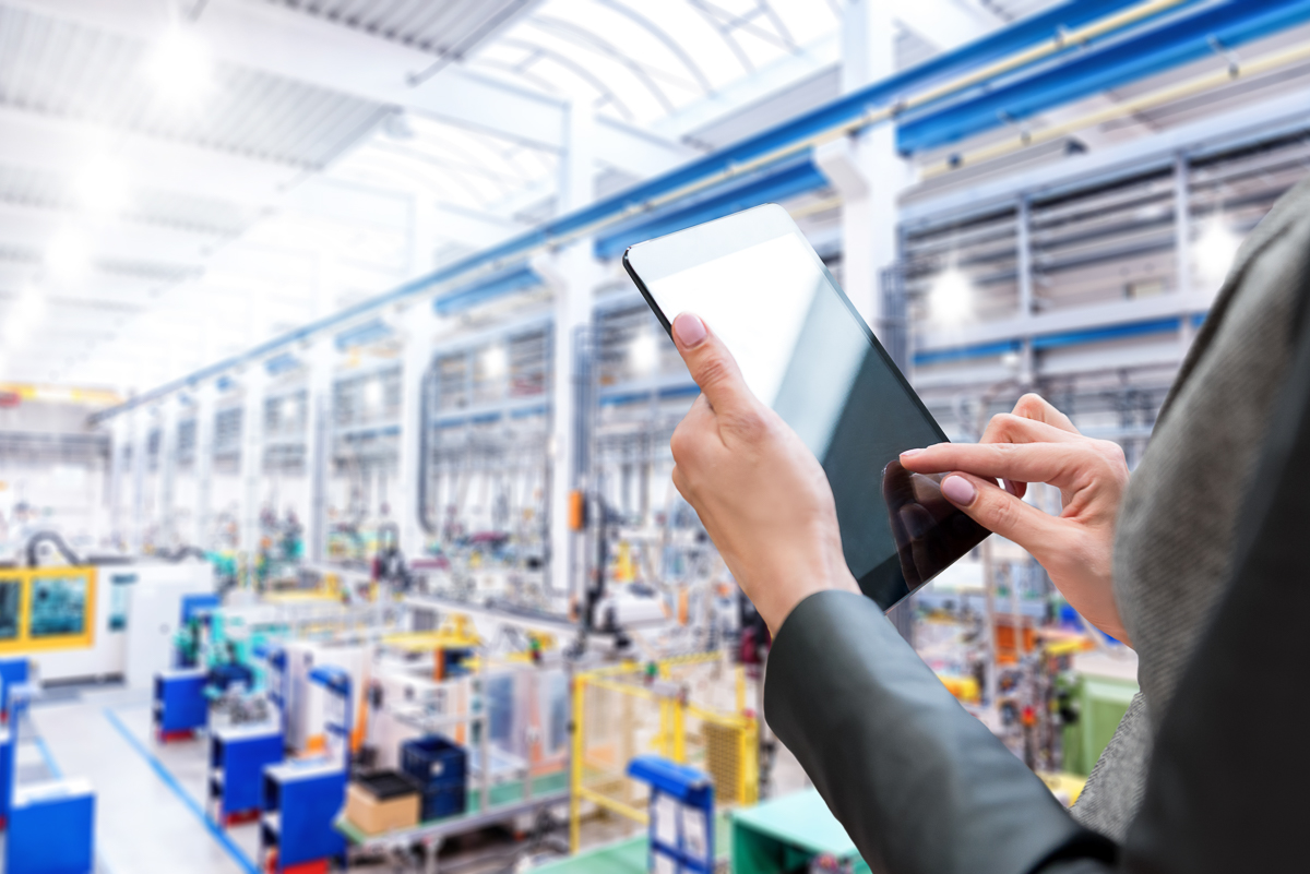 A professional monitoring processes with a tablet in a bright manufacturing facility