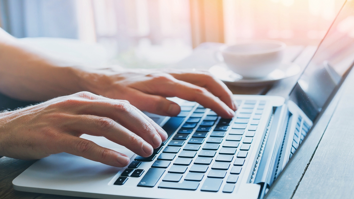 A close-up of hands typing on a laptop keyboard 