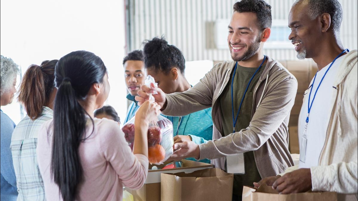 Volunteers at a food bank smiling and handing out groceries