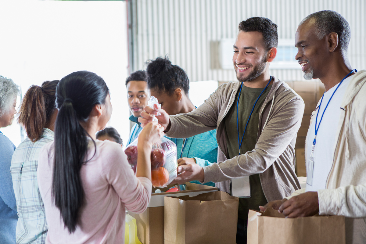 Volunteers at a food bank smiling and handing out groceries