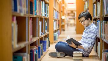 Young university student reading book in library
