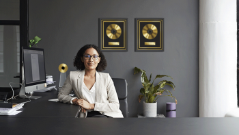 female at desk with gold record awards on the wall and a music award on her desk